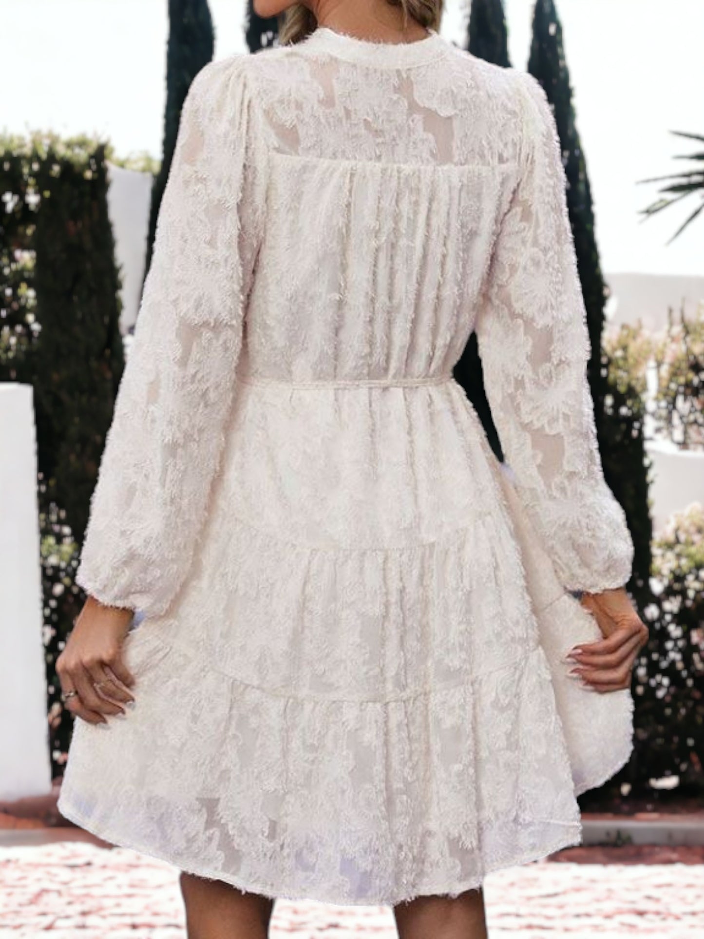 Vestido corto con volantes, cintura anudada, mangas largas y detalles de encaje texturizado